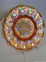 Front view of marigold carnival glass plate with Heavy Grape pattern