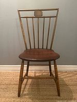 Front view showing spindle back, crest rail plaque, contoured seat