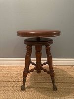 Full view of piano stool showing seat, legs, and claw feet