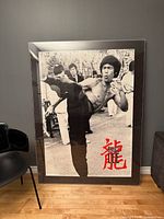 Full view of framed Bruce Lee poster leaning against wall