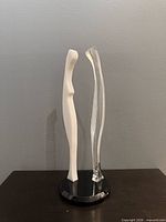 Front view of abstract white and clear lucite sculpture on black round base