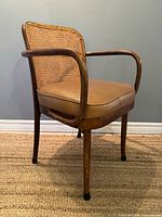 Three-quarter view of armchair showing bentwood arms, cane back, vinyl seat
