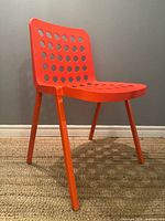 Left front angled view of orange Pedrali Koi-Booki 370 chair showing seat, back perforations and two legs