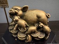 Close-up of brass pig family atop coins and ingots