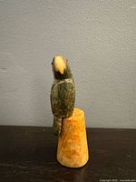 Full view of carved stone parrot on base
