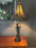 Full view of lamp lit with shade on wooden surface