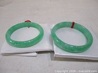 Two green jade bangles on white pads