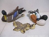 Two adult duck sculptures and duckling group shown together