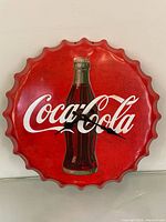 Front view of Coca-Cola bottle cap wall clock showing logo, bottle graphic, clock hands, and scalloped edges