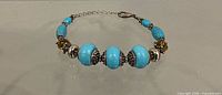 Full view of adjustable turquoise and crystal beaded bracelet showing bead arrangement, clasp and extender