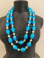 Necklace displayed on bust showing double strands of blue ribbed beads with pale spacers