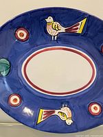 front view showing full platter and painted bird motifs
