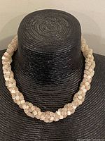 Full view of braided glass necklace on display bust