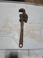 Full view of pipe wrench front side showing overall length and rust