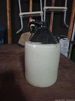 Front view of beige stoneware jug with dark brown glazed top and handle