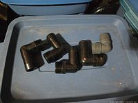 Six plastic 90° elbow fittings on blue tote