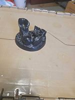 Front view of black resin baby shoes figurine on round base