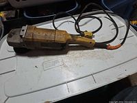 Left side view of DeWalt angle grinder showing housing, wheel, cord and plug