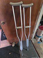 Full view of the pair of aluminum crutches leaning against door