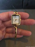 Front view of Infinite gold-tone bangle watch showing white dial and case