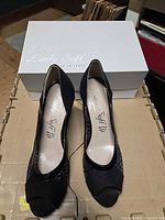 Pair of Lady Soft black peep toe heels in front of branded box