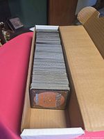 Stack of Magic: The Gathering cards in open cardboard storage box