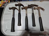 Five Mastercraft claw hammers laid out side by side on a plastic surface