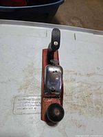 Top view showing chrome cap, red body, black knob, wood handle