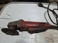 Left side view of Milwaukee angle grinder showing body, gear housing, mounted disc, cord