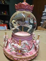 Front view of musical carousel snow globe showing main horse inside globe and ornate base