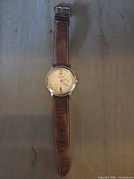 Front view of watch laid flat showing full strap and dial