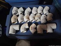 Tray with eighteen white PVC elbow fittings, mix of 90° and 45°