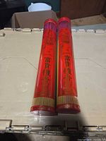 Two sealed red plastic tubes of sandalwood incense sticks