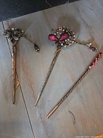 All three antique gold hair sticks on surface