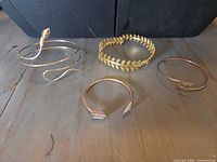 All four bracelets laid out: snake coil, laurel cuff, arrow cuff, thin bangle