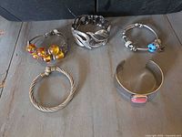 Five bracelets laid out on wooden surface