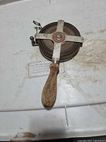 Full view of open-reel measuring tape showing wooden handle and steel cross-frame reel