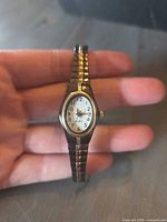 Front view of small oval two-tone women's wristwatch showing dial and case