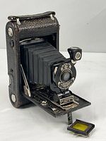 Front view of Kodak folding camera open with yellow filter on door