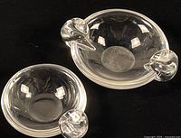 Both Steuben crystal ashtrays side by side showing relative size and scroll handles