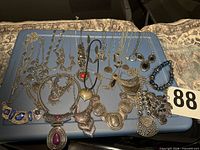 All 25 silver-tone necklaces arranged on blue surface