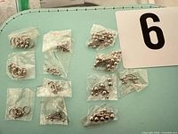 Full lot overview showing multiple sealed bags of assorted surgical steel body jewelry next to number card