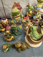Group shot of multiple frog prince figurines showing variety of designs and sizes