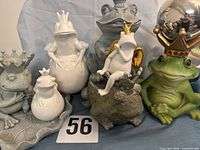 Group shot of all seven frog figurines showing sizes, materials and crowns