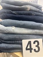 Stack of eight denim items with lot marker