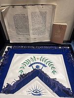 Open carrying case displaying apron, loose ritual pages, manual booklet