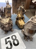 Group shot of five metal frog prince statues on table