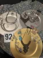 Overview of three charger plates displaying multiple necklace-and-earring sets