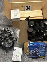 Lot overview showing boards, spray nozzle box, pathway spotlights, hanging lights bundle, icicle lights box