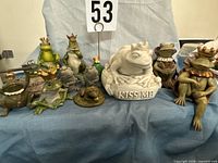 Group shot of ten assorted frog statues on blue cloth